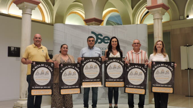 Los participantes en el acto de presentación en la Casa de la Provincia, con el cartel de la XI Ruta de la Tapa de Benacazón.